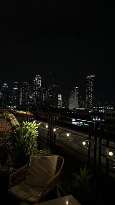 the city skyline is lit up at night from an outdoor patio with wicker furniture