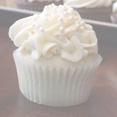 cupcakes with white frosting and sprinkles sitting on a table