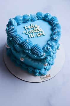 a blue heart shaped cake sitting on top of a white plate with writing on it