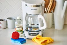 a white coffee maker sitting on top of a kitchen counter next to a yellow towel