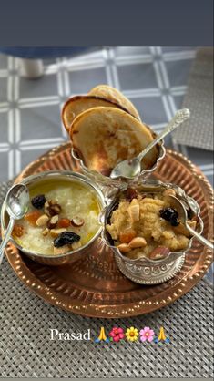 three bowls of food on a plate with spoons and bread in the back ground