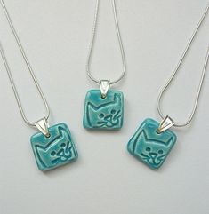 three necklaces with cats on them sitting next to each other