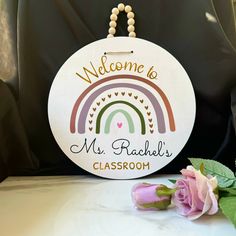 a sign that says welcome to mr rachel's classroom with a rose on the table