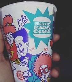 a person holding up a cup with cartoon characters on it