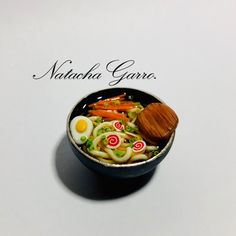 a bowl filled with noodles, carrots and an egg on top of a table