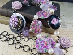 This 28 inch beaded lariat necklace  with a 6 inch pendant featuring some of my own resin art pendants. The main pendant has vintage lavendar enameled chrysanthemum and  dream charm embedded in the resin. Another charm has a resin rose caboschon. There are fresh water pearls, amethyst chrystal beads and mother of pearl coins with a floral print. I also added to the assemblage vintage bakelite roses and an enamaled pink rose caboschon from a vintage pin. The last picture is other similar style pendants in my shop sold separately. One Of A Kind Artisan Purple Jewelry, Artisan One-of-a-kind Purple Jewelry, Artisan Lariat Jewelry Gift, Artisan Lariat Necklace Gift, Unique Vintage Jewelry With Lobster Clasp, Artisan Lariat Jewelry As Gift, Artistic One-of-a-kind Dangle Jewelry, Handmade Artisan Lariat Necklace For Gift, Artistic Hand Painted Purple Jewelry