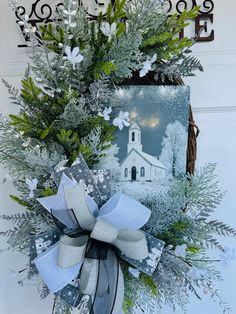 a christmas wreath hanging on the front door of a house with a church in the background