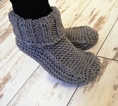 a pair of gray knitted slippers sitting on top of a wooden floor