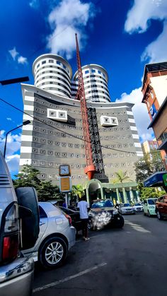 cars parked in front of a tall building with a crane on it's side