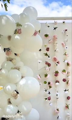 white balloons and flowers are hanging from the ceiling