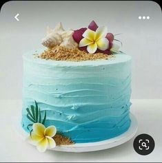 a blue cake with flowers and shells on top