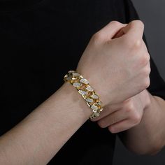 Put some Cuban flavor into your style with this 18mm Cuban link bracelet. It's crafted with high quality gold plating and adorned with cubic zirconia stones for a touch of luxury. The Cuban link design is classic and stylish, and it's sure to make a statement whether you're dressing up or dressing down.This bracelet is the perfect way to add a little bit of edge to your outfit. Whether you're going for a night out on the town or just hanging out with friends, this bracelet will help you make a s Gold Diamond Chain Bracelet With Rhinestones, Iced Out Gold Chain Link Bracelet, Gold Cuban Link Bracelet Iced Out In Cubic Zirconia, Gold Cuban Link Bracelet Iced Out With Cubic Zirconia, Gold Iced Out Cuban Link Bracelet, Gold Iced Out Cuban Link Bracelet With Cubic Zirconia, Gold Cuban Link Bracelet With Bling, Gold Cuban Link Diamond Bracelet Iced Out, Gold Cuban Link Chain Bracelet With Cubic Zirconia