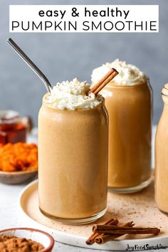 two mason jars filled with pumpkin smoothie and topped with whipped cream, cinnamon sticks