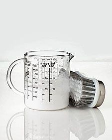 a measuring cup filled with sugar and a brush