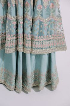 Ice Blue Traditional Pishwas for Indian Wedding Wear is all set to make a lasting impact in its divine royalty with a heavy base and work of our special artisans. Pishwas: In a refreshing light sea green shade, this dreamy and celestial nylon net pishwas is gracefully crafted in a front open silhouette and exquisitely adorned with beautiful floral motifs embroidered at the front, back, and sleeves in soft pink and luscious green hues. A pure representation of grandeur and sophistication, this sc Pink Desi Wedding Dress, Light Sea Green, Desi Wedding Dresses, Sea Green Color, Indian Wedding Wear, Desi Wedding, Green Hues, Net Fabric, Light Blue Green