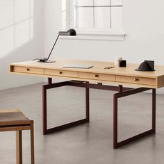 a wooden desk with two drawers and a lamp on top, in an empty room