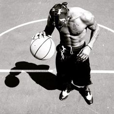 a shirtless man holding a basketball on a court