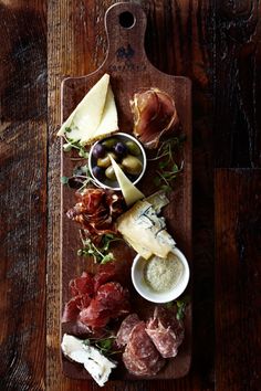 a wooden cutting board topped with meat and cheese