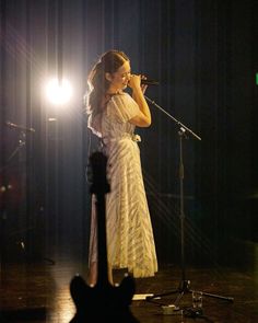 a woman in a white dress singing into a microphone