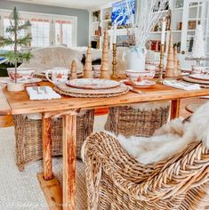 a dining room table set with wicker chairs and place settings on the wooden table