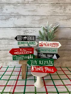 several wooden signs sitting on top of a white table next to a potted plant