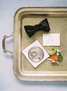 a silver tray with a black bow tie and other items