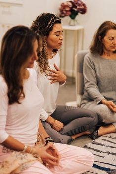 three women are sitting in a circle doing yoga exercises with one woman holding her hand out