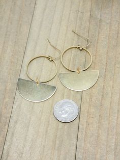 Add a touch of modern sophistication to your look with our lightweight brass statement earrings. The geometric design of these half circle earrings, inspired by the bohemian style, will make you stand out in any crowd. Made from solid raw brass, they are the perfect addition to your collection for a bold and elegant statement. Solid raw brass Brass ear hooks Drop 2" Created in studio - Wilmington, NC Modern Matte Gold Brass Hoop Earrings, Modern Crescent Brass Earrings, Minimalist Brass Half Moon Jewelry, Minimalist Half Moon Brass Jewelry, Modern Crescent Brass Hoop Earrings, Gold Half Moon Brass Earrings, Gold Brass Half Moon Earrings, Bohemian Brass Circle Earrings, Minimalist Circle Brass Earrings