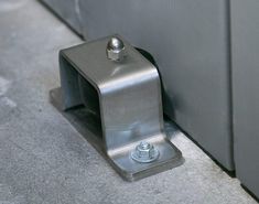 a close up of a metal object on the ground next to a door with a screw in it