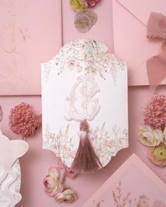 the wedding stationery is laid out on top of pink and white paper with flowers