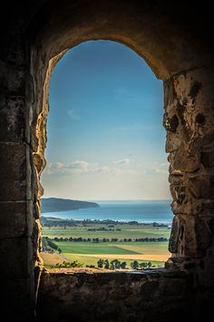 an open window with a view of the ocean and land in the distance, looking out to sea