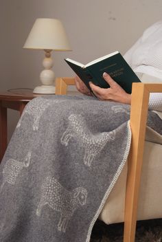 a person sitting on a chair reading a book while holding a blanket over their head