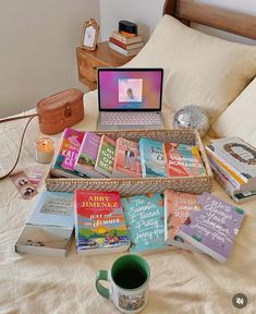 a bed topped with lots of books next to a laptop