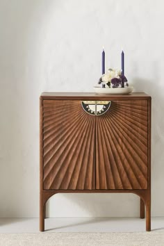 a wooden cabinet with two candles on top