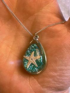 This silver necklace features a resin pendant with sea-green colored glitter and a tiny starfish inside. It's a beautiful addition to any ocean lover's jewelry collection. Starfish Necklace, Ocean Lover, Sea Green, Resin Pendant, Starfish, Resin Jewelry, Resin Crafts, Necklace Etsy, Silver Necklace