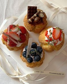 three pastries with strawberries, blueberries and strawberries on them