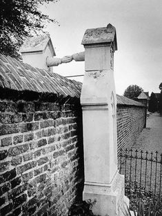 a black and white photo of an old grave on the side of a brick wall