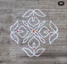 an image of a flower made out of white paint on wood with red dots in the middle