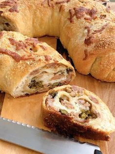 a pastry with meat and cheese is cut in half on a cutting board next to a knife