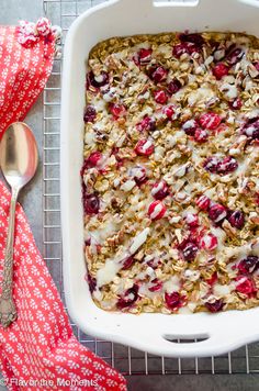 a white dish filled with granola and cranberries next to a red napkin