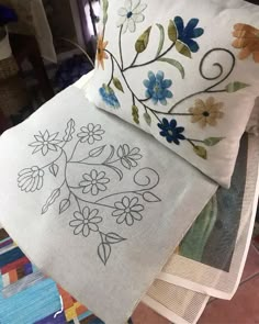 three embroidered pillows sitting on top of each other in front of a quilting machine