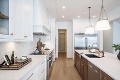 a large kitchen with white cabinets and wood flooring is seen in this image from the front view