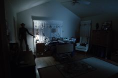 a person standing in a dark room next to a bed