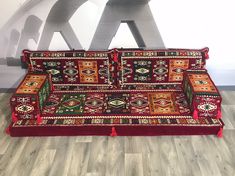 a red couch sitting on top of a wooden floor next to a white wall with letters