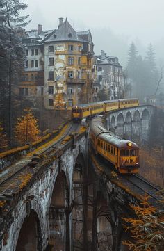 a yellow train traveling over a bridge next to tall buildings