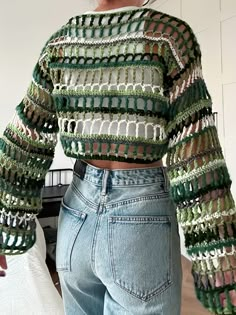 a woman wearing jeans and a cropped top with crochet on the sleeves