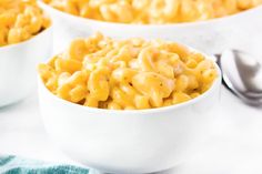 three bowls filled with macaroni and cheese on top of a white tablecloth