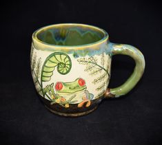 a green and white coffee cup with a lizard on it