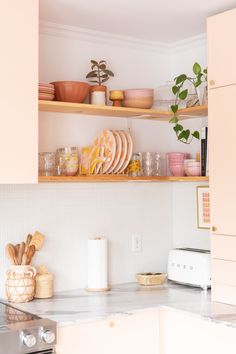 the shelves above the kitchen sink are filled with dishes and utensils for cooking