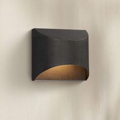 a black and gold light fixture on a wall with a white background in the corner